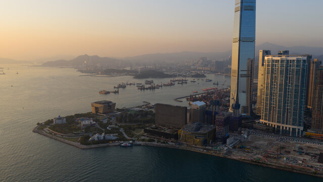 Hong Kong, Hong Kong - 13 February 2026: Aerial view of a sprawling cityscape where the iconic International Commerce Centre pierces the hazy sky, contrasting with the muted tones of the harbor below.