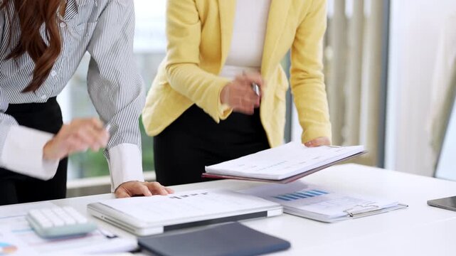 Close up hands of Business partners working with analysis report and advisor showing plan, Two businesswoman working with Financial analysts reports and planning investment at office.