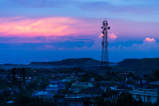 Cherrapunji, India - 25 July 2023: View of the towering telecommunications tower piercing through the vibrant twilight sky above the misty town.