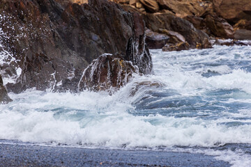 Fototapeta premium The white spray from the waves crashing against the rocks