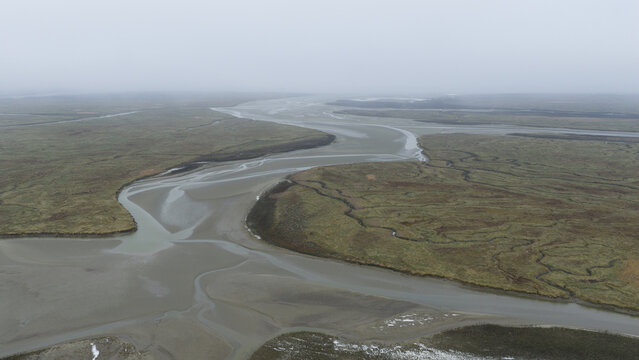 Aerial view of the winding waterways cutting through marshland, a symphony of grey and green under a cloudy sky, 4 Emmaweg, Nieuw Namen, Zeeland, Netherlands.