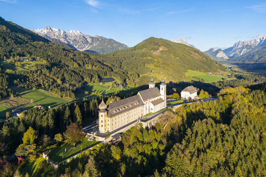 Aerial view of the Wallfahrtskirche Frauenberg an der Enns, bathed in golden light against the backdrop of the majestic mountains, Wallfahrtskirche Frauenberg an der Enns, Steiermark, Austria.