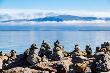 Stones towers with a ocean sea and a mountain with clouds in the background.. Stack of stones. Balanced rocks. Zen. Peaceful state of mind. Harmony.  Relax concept