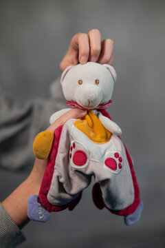 main faisant un c&acirc;lin &agrave; un doudou, une peluche pour b&eacute;b&eacute; blanche rouge et orange