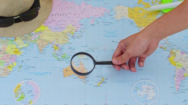 Close-up of traveler searching for destinations on world map with magnifying glass
