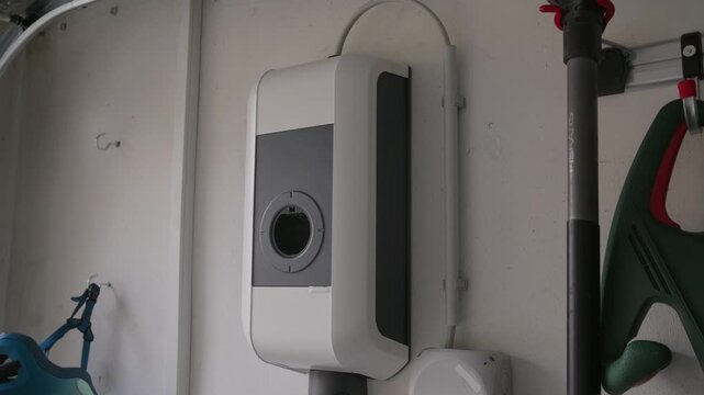 Technician performing a software update on an electric vehicle charging station. Inserting a USB flash drive into the internal port and activating the update process via button.