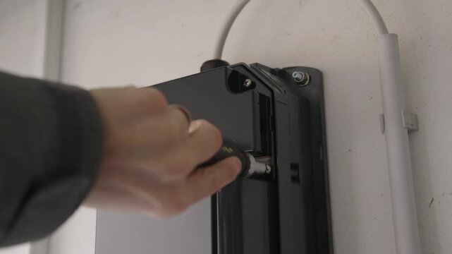 Close-up of an EV charging station being opened. The internal electronics, DIP switches, wiring terminals, and flashing status LEDs are visible during configuration or repair.