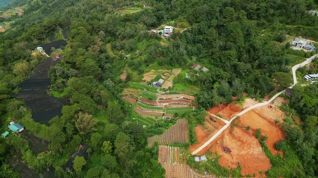 Panoramic aerial pullback of lush mountain slopes with layered farmland amid dense greenery - Benguet, Philippines