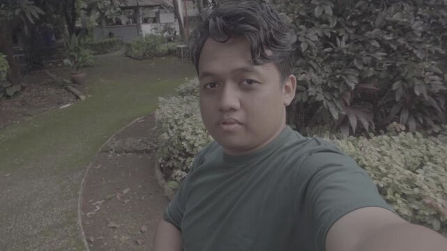 A Southeast Asian man sits alone in a park while filming himself showing the public park around him. S-Log3, S-Gamut3.Cine