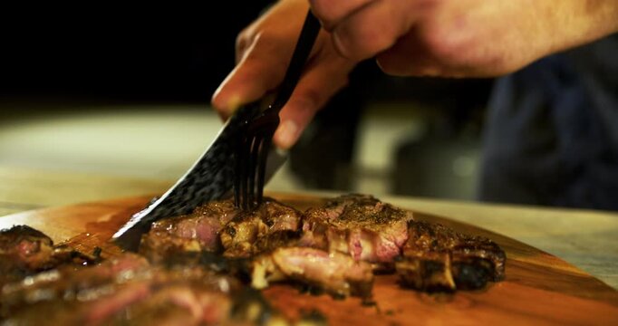 Closeup on knife cutting up hot, juicy steak on counter