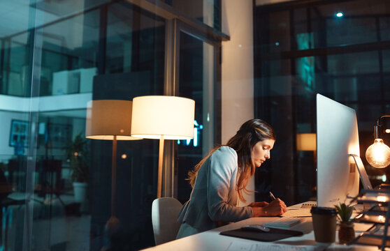 Computer, woman and writing notes in office at night for trade details, price targets and entry date. Global trader, PC and stocks journal at desk for market trends, performance results and planning