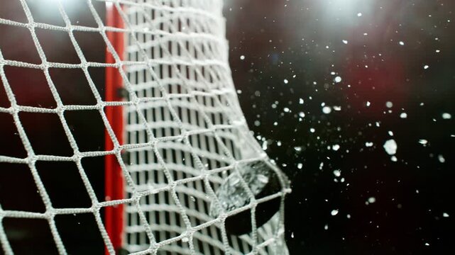 Super slow motion of ice hockey puck hitting the back of the net as it scores a goal