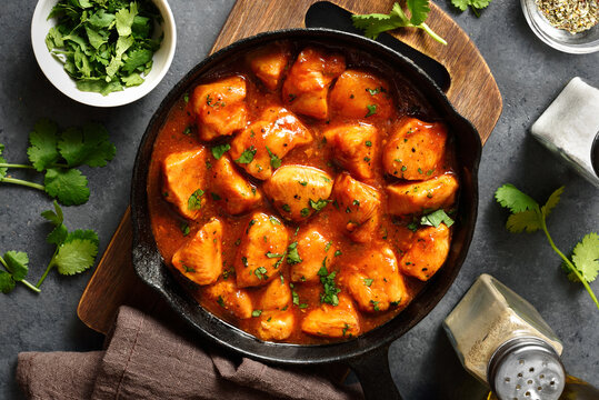 Sweet and spicy chicken bites with sauce in cast iron pan, top view