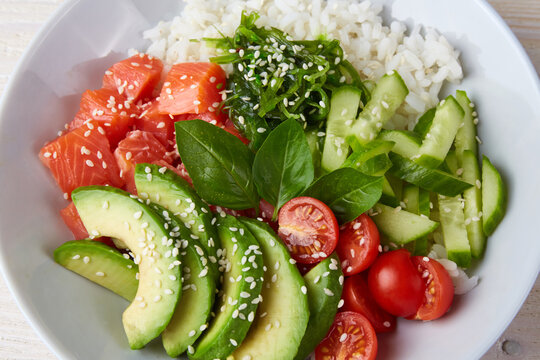 Poke bowl with salmon, rice, avocado, cucumber, mango, micro green and carrot. Hawaiian diet food with fish .