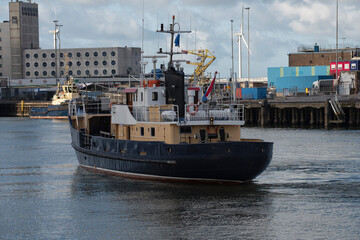 Fototapeta premium Training Ship sails on the North Sea Canal towards the quay with industrial buildings and cranes in the background