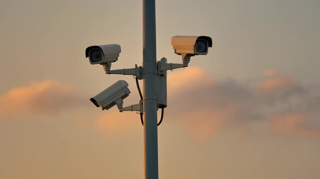 Security cameras on pole at sunrise or sunset with cloudy sky