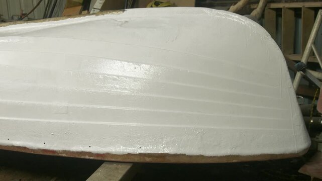 Upturned fiberglass fishing boat painted with white topcoat polyester paint