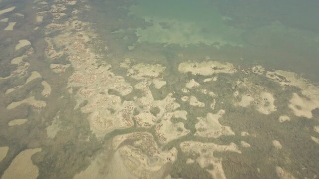 Smooth 4K UHD drone flies forward and descends over the Grado Lagoon, revealing shallow water, sandbanks and abstract tidal patterns&mdash;ideal for nature b-roll, docs.