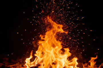 Fototapeta premium A Dynamic Close-up of a Roaring Bonfire with Brilliant Orange Flames and Countless Flying Sparks Against a Deep Dark Background, Symbolizing Energy and Destruction