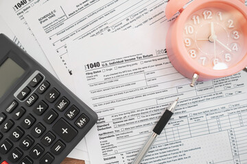 US individual income tax return form 1040 with calculator and alarm clock. Tax filing deadline and financial planning concept