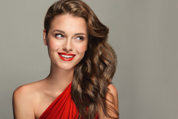 A slender and elegant woman with a beautiful smile. She is wearing a red dress and red lipstick....