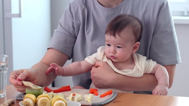  A baby picking and eating food from a sectioned plate with her fingers. The concept of weaning is based on the principle of "child-choosing food," independent feeding, healthy breakfast, and fine mot