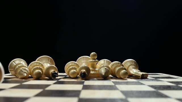 White chess pieces on a black background stand in a row, and the chess player's hand passes over them, knocking them down onto the game board. 4к