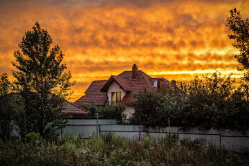 Red tile roof under orange sky at sunset
