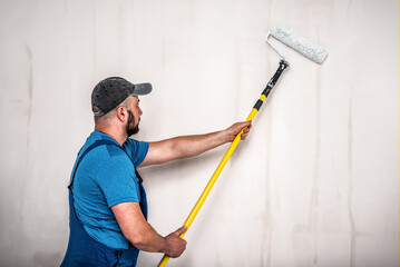 Worker master in blue is ready for wall painting with roller