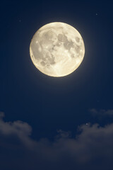 Fototapeta premium Full Moon Glowing Brightly in Deep Blue Night Sky with Wispy Clouds and Scattered Stars Visible Around Celestial Body