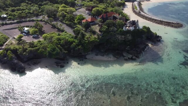 Cinematic aerial drone moving right near temple on the cliffs at Geger Beach, Nusa Dua, Bali, Indonesia.