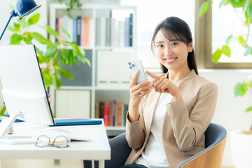 オフィスでスマホを使うビジネスウーマン