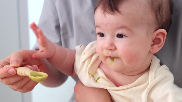  A baby picking and eating food from a sectioned plate with her fingers. The concept of weaning is based on the principle of "child-choosing food," independent feeding, healthy breakfast, and fine mot
