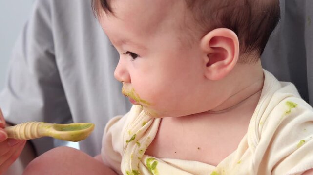  A baby picking and eating food from a sectioned plate with her fingers. The concept of weaning is based on the principle of "child-choosing food," independent feeding, healthy breakfast, and fine mot