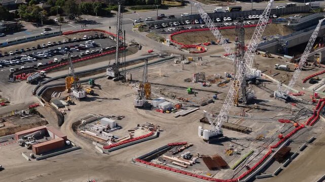 Aerial dolly over dusty construction site with large crawler cranes and piling machines. Construction on tunnel on outskirts of Melbourne CBD.