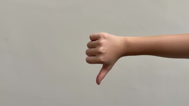 A child hand shows thumbs up and then thumbs down, changing gestures to express opposite reactions against a clean background.