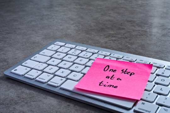 "One step at a time" sticky note left on keyboard. The bright note stands out against the keys, symbolising motivation, productivity, and a focused mindset.
