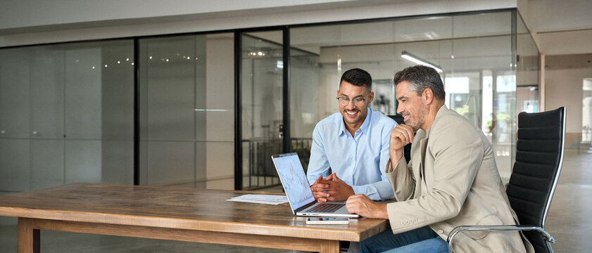 Stock exchange market traders investors working on financial trading charts analysis. Two happy busy business men analysts consulting on digital finance forecast using laptop in office. Copy space.
