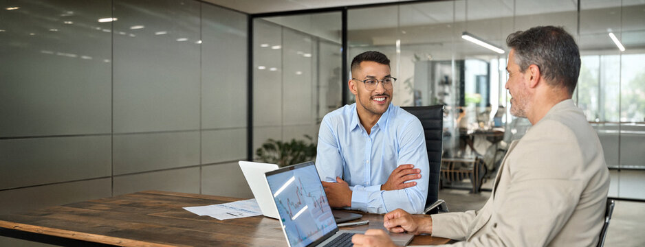 Stock exchange market traders working on financial trading charts analysis. Two happy busy business men analysts or advisor and investor consulting on digital finance forecast using laptop in office.
