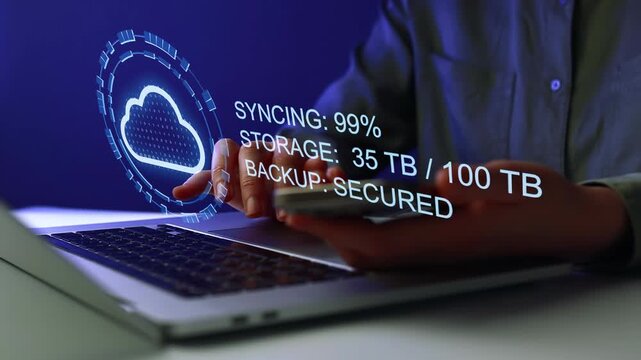 Cloud storage sync in progress with digital display on laptop and hand using smartphone.
