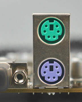 silver metallic ps2 housing on motherboard, green and purple plastic ports for mouse and keyboard, closeup with soft focus, legacy computer hardware and peripheral connectivity concept