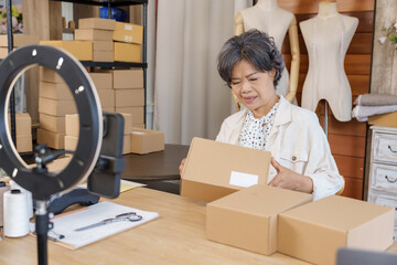 Senior asian mother checking carton box preparing fashion order for family small business ecommerce...