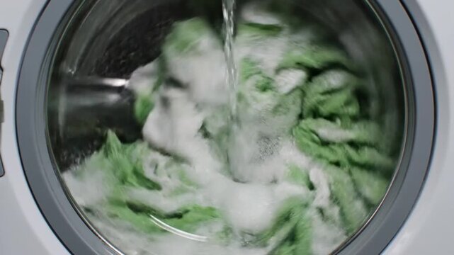 Washing Machine Cycle with Green Clothes and Soap.