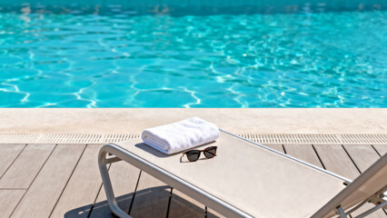 Obraz premium Poolside lounge chair with towel and sunglasses