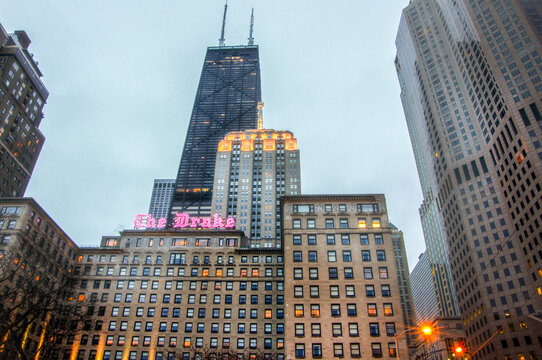 Chicago, IL&mdash;March 29, 2018; The Drake Hotel&rsquo;s illuminated sign sits beneath the John Hancock Center as evening lights reflect across the Gold Coast skyline.