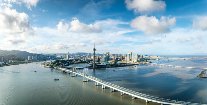 High angle panoramic view of modern city skyline and coastal bridges in Macau, China.
