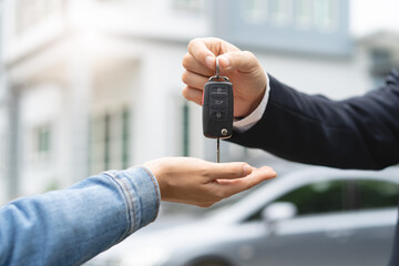transportation rental automotive business concept. Close up hands of rental auto agent giving car remote key to client to travel sightseeing.