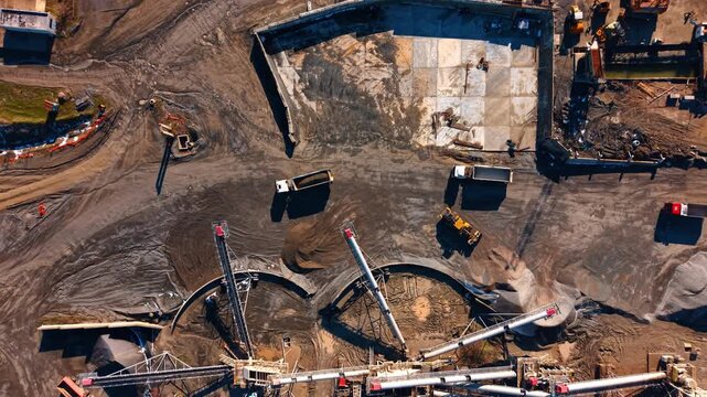 Heavy truck and loader working at industrial granite quarry. Aerial shot of dump trucks and a yellow front loader moving stone near a crushing plant.