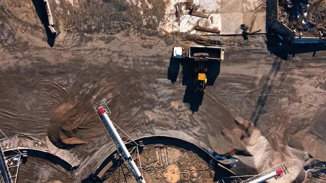 Top down view of loader loading truck at granite quarry. Aerial shot showing the process of stone loading into a heavy dump truck.