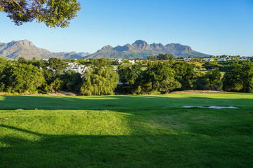 South Africa,Winery in Stellenbosch ,A serene golf course with lush green fairways, trees, and distant mountains under a clear blue sky. © SHUNJI ZHOU